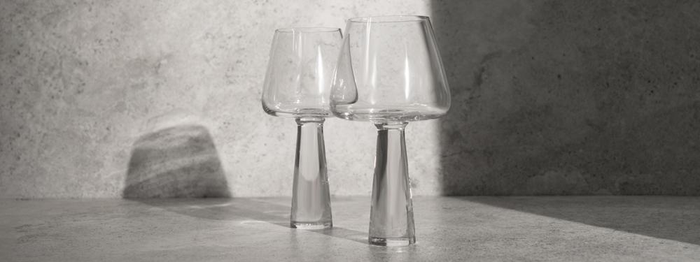 Close-up of two elegant wine glasses with geometric design, casting shadows on a concrete surface.